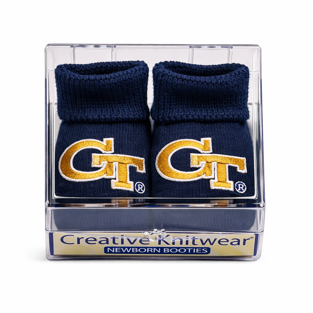 Navy baby booties with gold 'GT' logo in a clear packaging box, brand 'Creative Knitwear' visible.